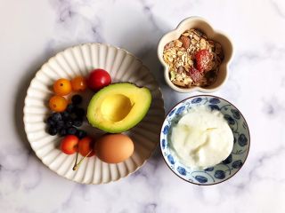 水果麦片酸奶碗,首先我们准备好所有食材：
水果坚果燕麦片适量，老酸奶适量，牛油果半个，小番茄数个，熟鸡蛋一个，蓝莓数粒，樱桃两颗（这里的用量并没有标准，因为要看你所用的碗有多大，碗小一点食材就用少一点，碗大一点食材就多一点，水果的话你也可以用你所喜欢的）